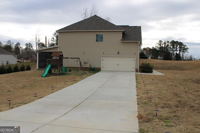 view of side of property with a playground, a garage, and a lawn