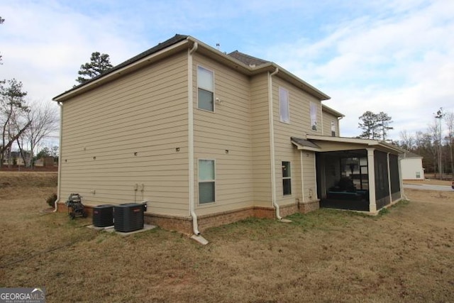 rear view of property featuring a sunroom, central AC unit, and a yard