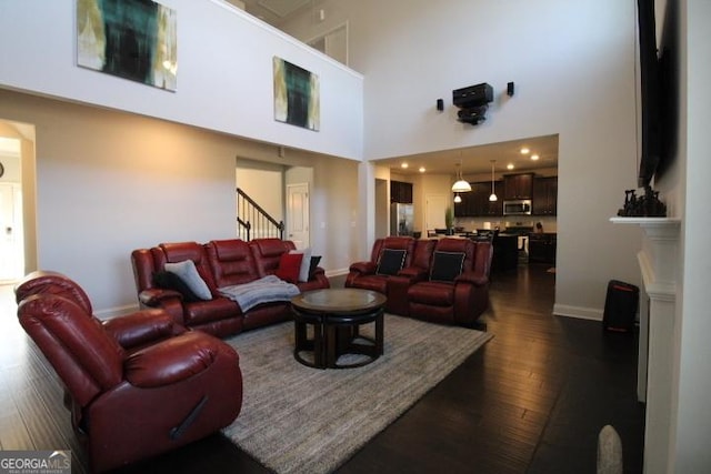 living room with dark hardwood / wood-style flooring and a towering ceiling