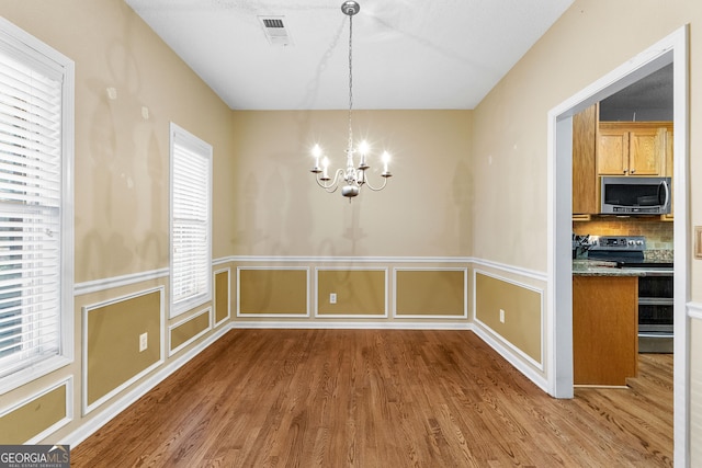 unfurnished dining area featuring a notable chandelier and dark hardwood / wood-style floors