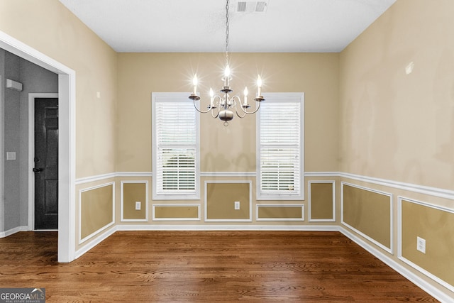 unfurnished dining area featuring wood-type flooring and a notable chandelier