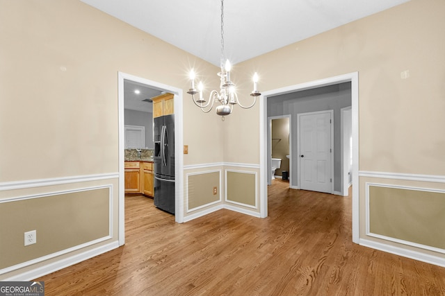 unfurnished dining area with a chandelier and light hardwood / wood-style floors