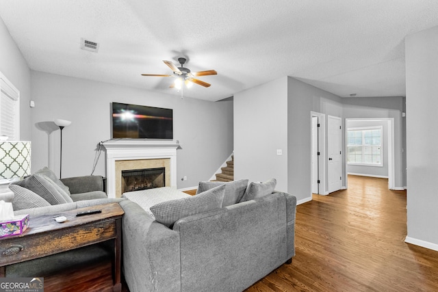 living room featuring hardwood / wood-style floors, ceiling fan, and a textured ceiling