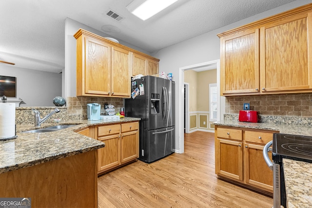 kitchen featuring backsplash, sink, light hardwood / wood-style floors, and stainless steel refrigerator with ice dispenser