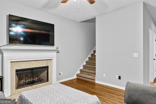 interior space with ceiling fan, light wood-type flooring, a textured ceiling, and a high end fireplace