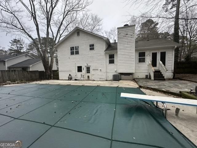 back of property with cooling unit, a patio area, and a covered pool