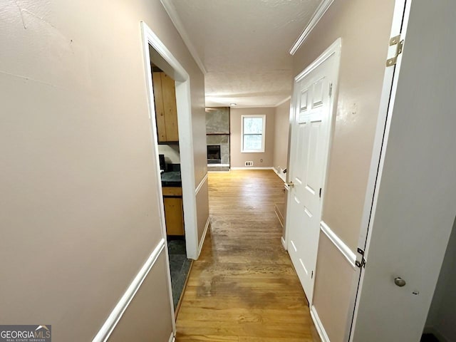 corridor featuring crown molding and light hardwood / wood-style floors