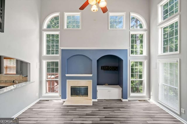 unfurnished living room with ceiling fan, light hardwood / wood-style flooring, and a towering ceiling