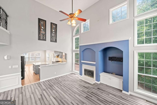 unfurnished living room featuring a high ceiling, light hardwood / wood-style flooring, and plenty of natural light