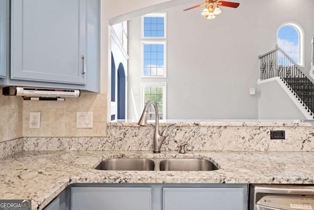 kitchen featuring tasteful backsplash, dishwasher, sink, and light stone countertops