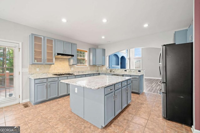 kitchen featuring backsplash, a wealth of natural light, stainless steel fridge, and a center island