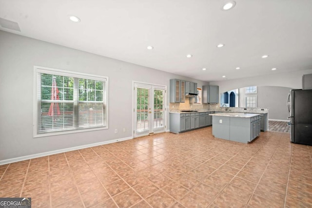 kitchen with gray cabinetry, sink, stainless steel appliances, a kitchen island, and light tile patterned floors