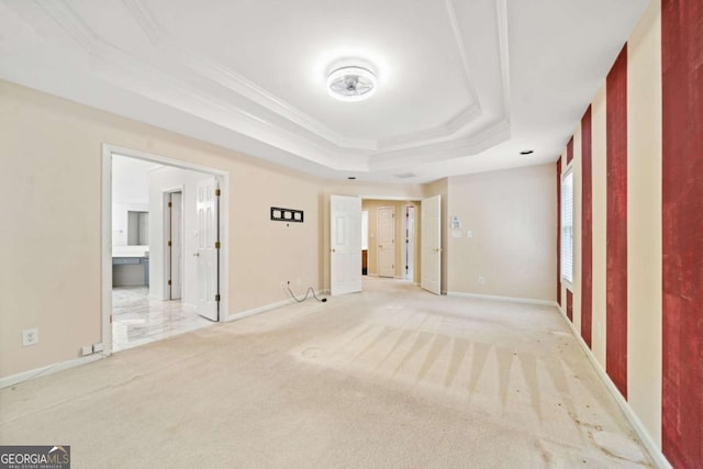 empty room with crown molding, light carpet, and a tray ceiling