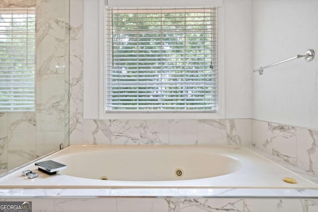 bathroom featuring a relaxing tiled tub and plenty of natural light