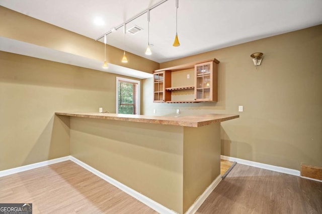 bar with pendant lighting, light hardwood / wood-style floors, and rail lighting