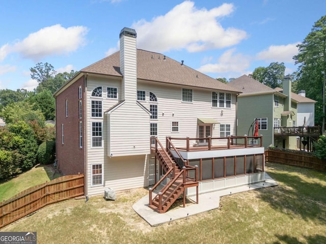 rear view of property with a wooden deck, a sunroom, and a yard