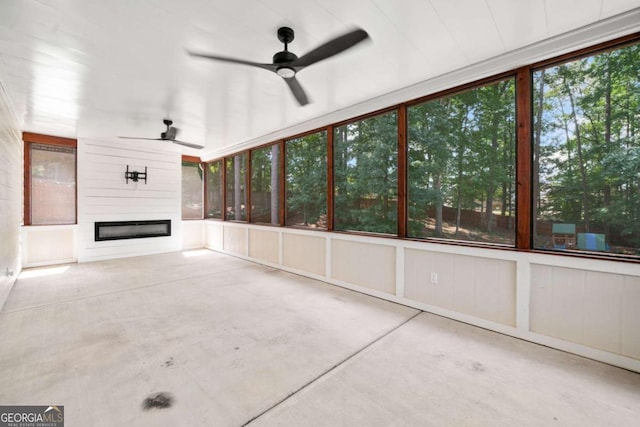 unfurnished sunroom featuring ceiling fan and a fireplace