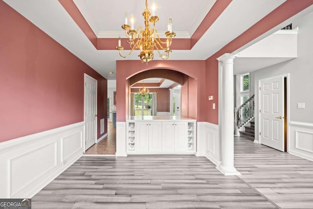 foyer entrance with a wealth of natural light, light hardwood / wood-style floors, a notable chandelier, and ornamental molding