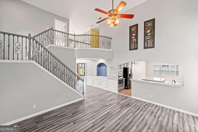 entryway with ceiling fan, wood-type flooring, and a high ceiling