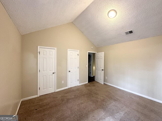 unfurnished bedroom with carpet flooring, a textured ceiling, and high vaulted ceiling