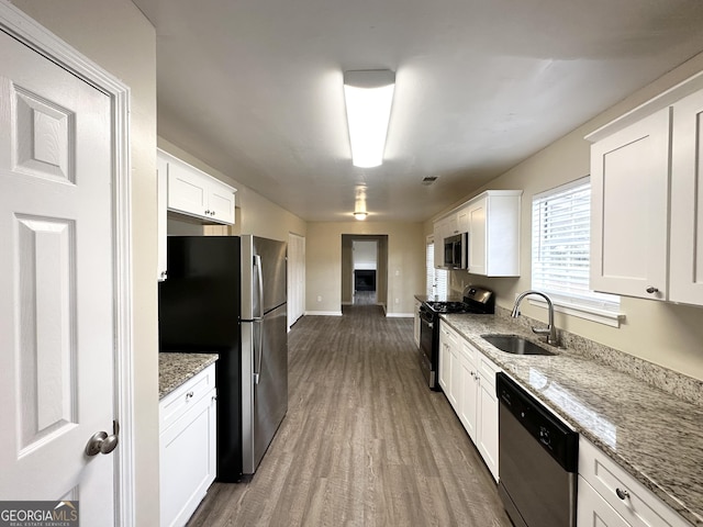 kitchen with sink, dark wood-type flooring, light stone counters, white cabinets, and appliances with stainless steel finishes