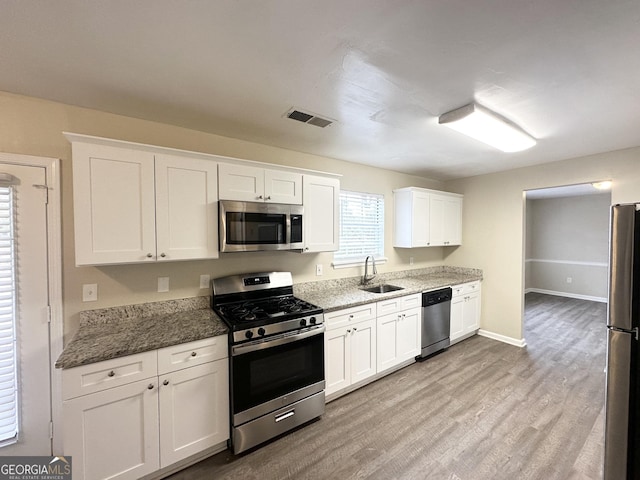 kitchen featuring sink, stainless steel appliances, light hardwood / wood-style floors, stone countertops, and white cabinets