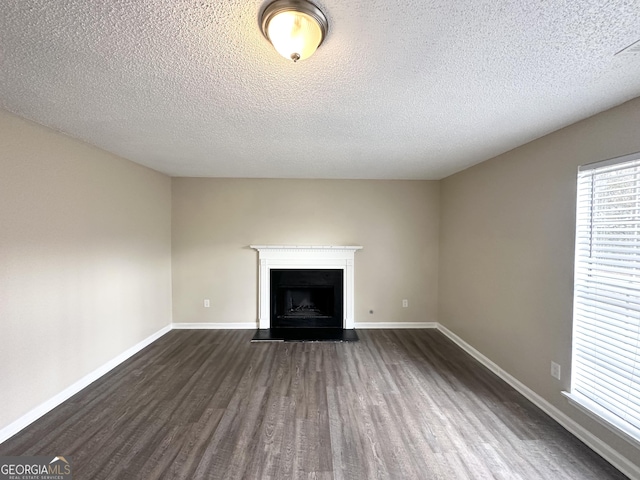 unfurnished living room featuring a textured ceiling and dark wood-type flooring