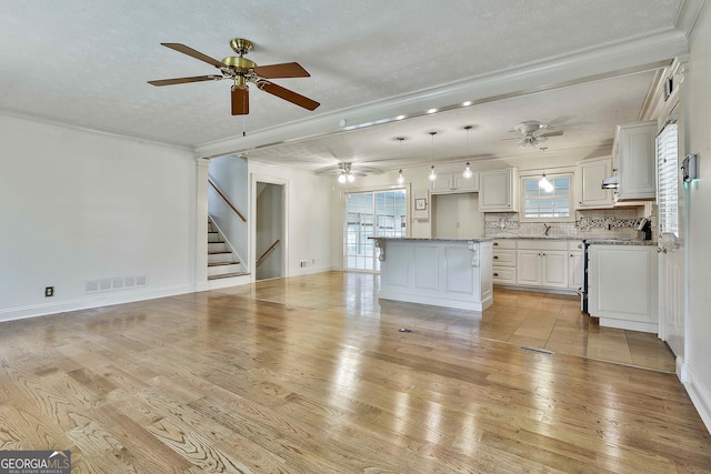 unfurnished living room featuring crown molding, sink, light hardwood / wood-style floors, and a textured ceiling