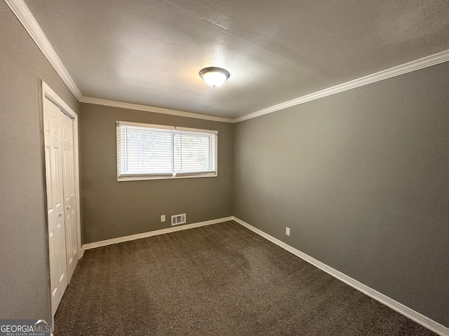 unfurnished bedroom featuring dark carpet, ornamental molding, and a closet