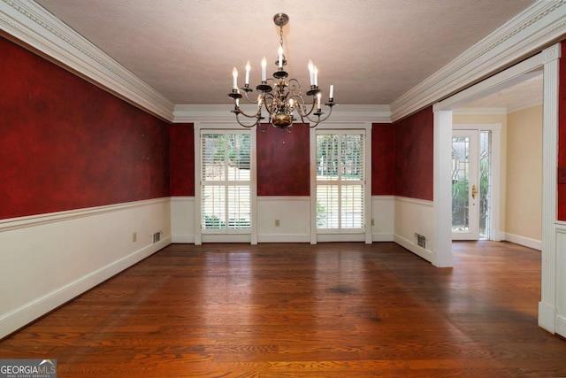 spare room with wood-type flooring, french doors, a textured ceiling, ornamental molding, and an inviting chandelier