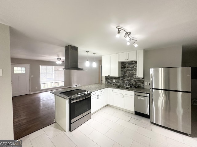 kitchen featuring kitchen peninsula, decorative light fixtures, island range hood, white cabinets, and appliances with stainless steel finishes