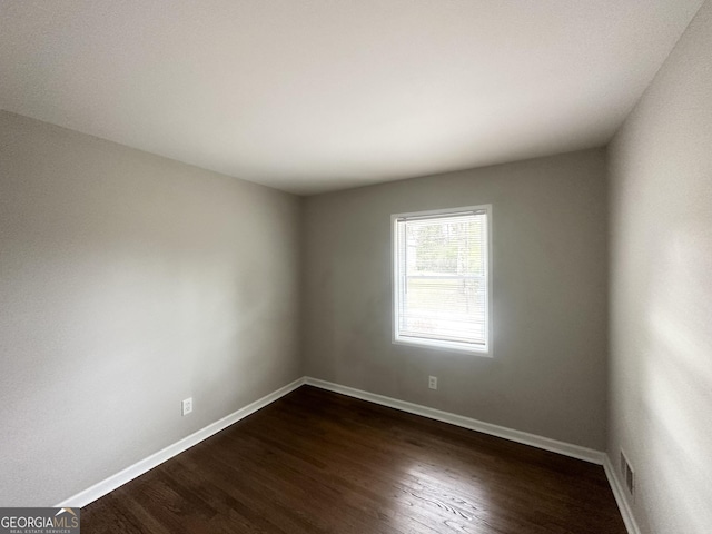 unfurnished room with dark wood-type flooring