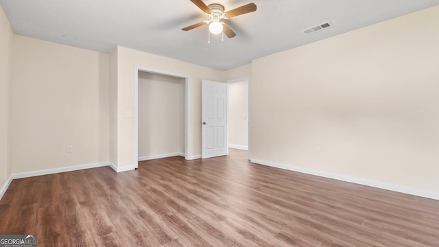 unfurnished bedroom with a textured ceiling, a closet, hardwood / wood-style flooring, and ceiling fan