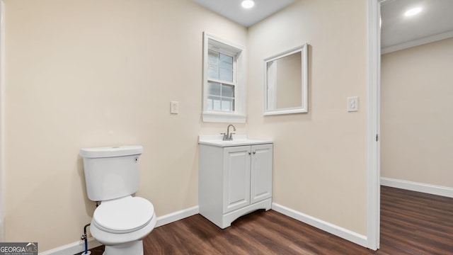 bathroom featuring ornamental molding, vanity, wood-type flooring, and toilet