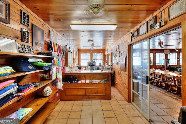 kitchen with light tile patterned floors, wooden ceiling, ceiling fan, and wooden walls