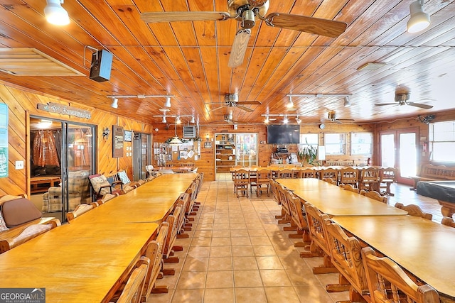 unfurnished dining area with wood walls, wood ceiling, light tile patterned floors, and track lighting