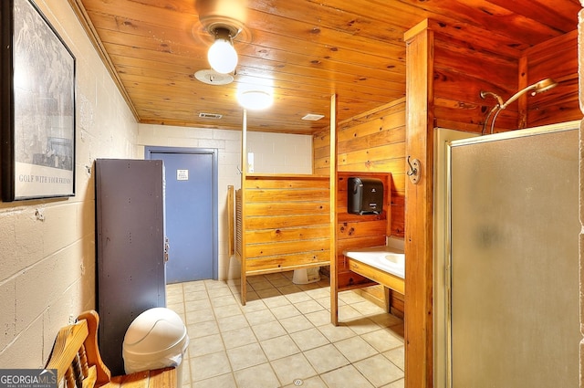 bathroom with tile patterned floors, wood walls, wooden ceiling, and walk in shower