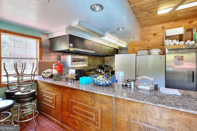 kitchen featuring stainless steel refrigerator, stainless steel built in fridge, dark tile patterned floors, and stone countertops