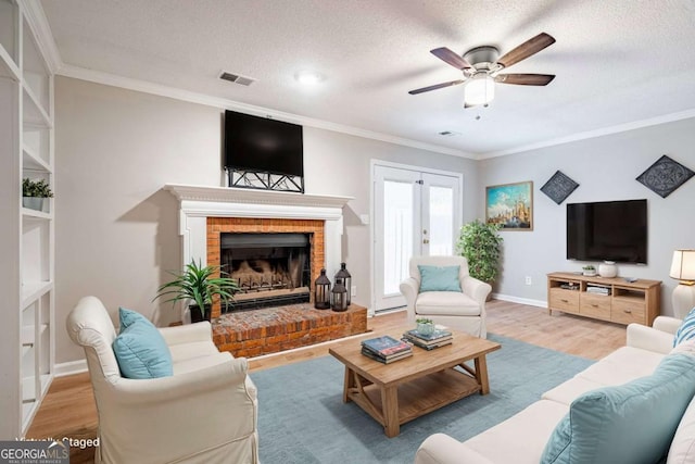 living room with french doors, light hardwood / wood-style floors, a textured ceiling, and ornamental molding