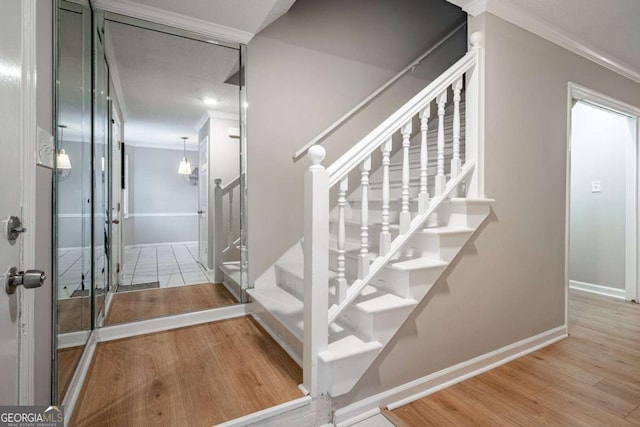 stairway with wood-type flooring and ornamental molding