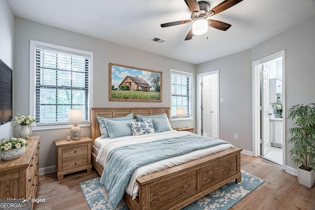 bedroom with multiple windows, ensuite bathroom, and light wood-type flooring