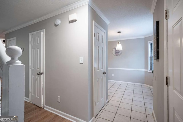 hall with crown molding, light tile patterned floors, and a textured ceiling