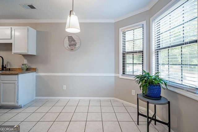 kitchen featuring white cabinets, pendant lighting, light tile patterned floors, and ornamental molding