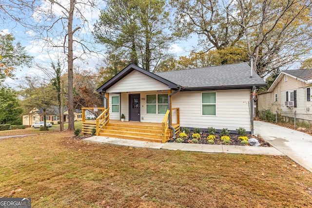 view of front facade featuring cooling unit, a front lawn, and covered porch