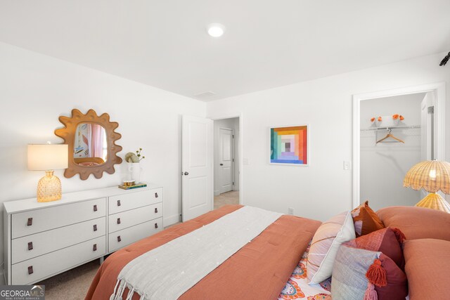 carpeted bedroom with a spacious closet and a closet