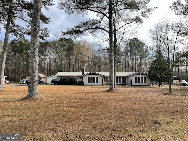 ranch-style home with metal roof, a chimney, and a front yard