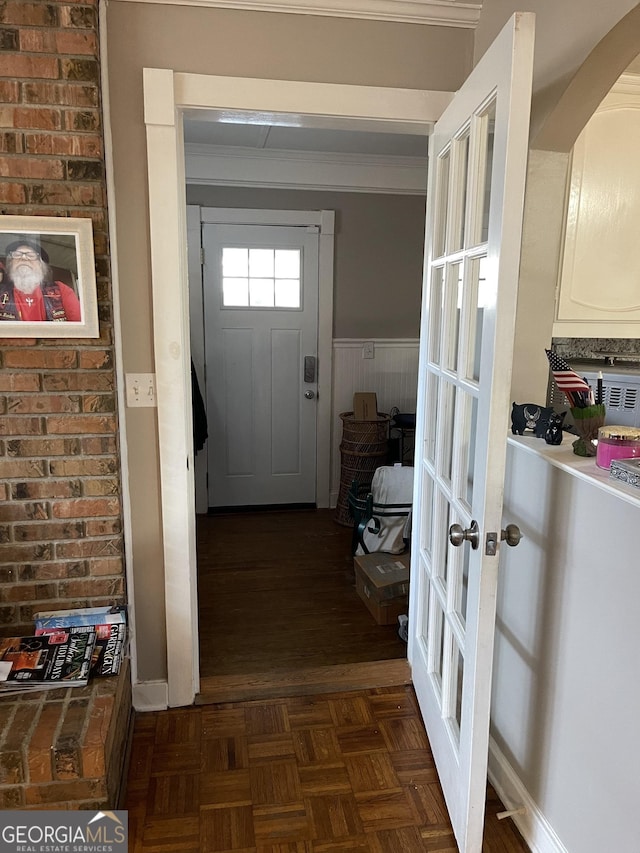 doorway to outside featuring wood walls, dark parquet floors, french doors, and ornamental molding