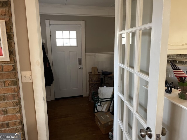 entryway with dark hardwood / wood-style flooring, ornamental molding, and brick wall