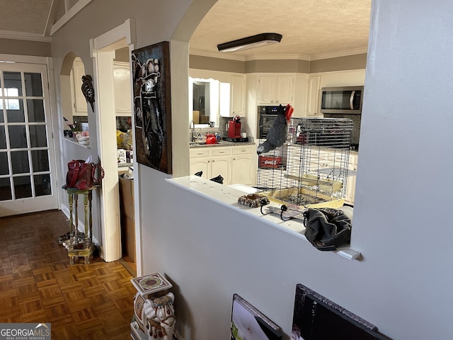 kitchen featuring arched walkways, black oven, stainless steel microwave, and a textured ceiling