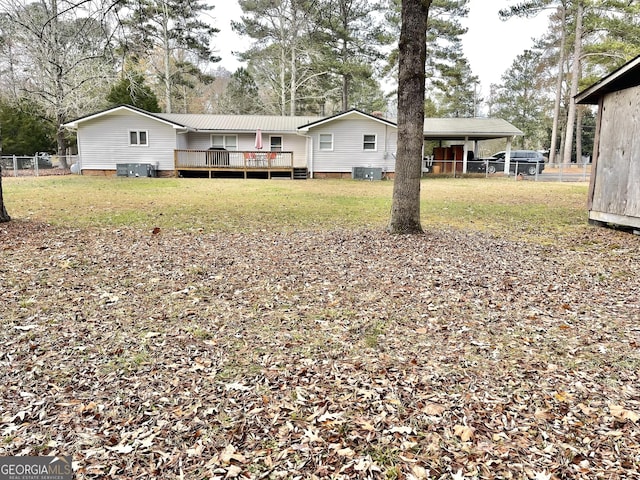 rear view of property featuring central AC, fence, a lawn, a wooden deck, and a carport